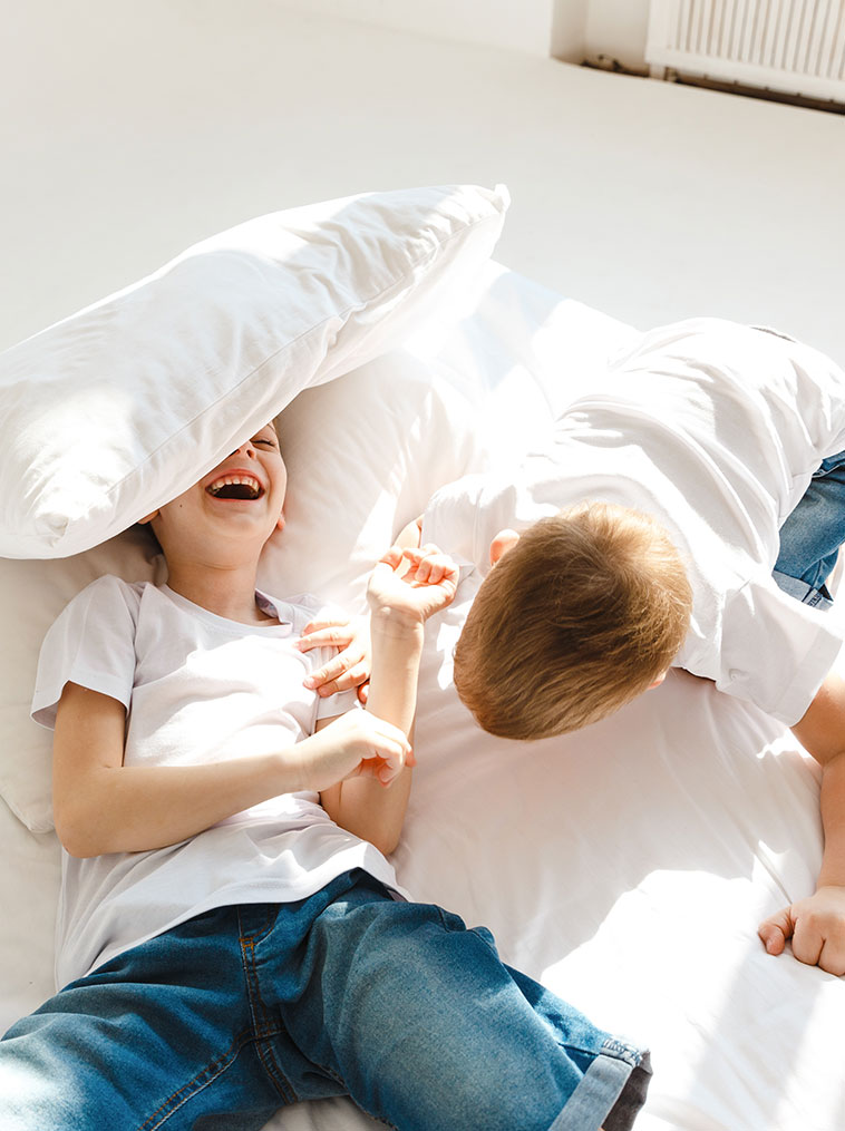 Two little boys laughing and having fun on a mattress